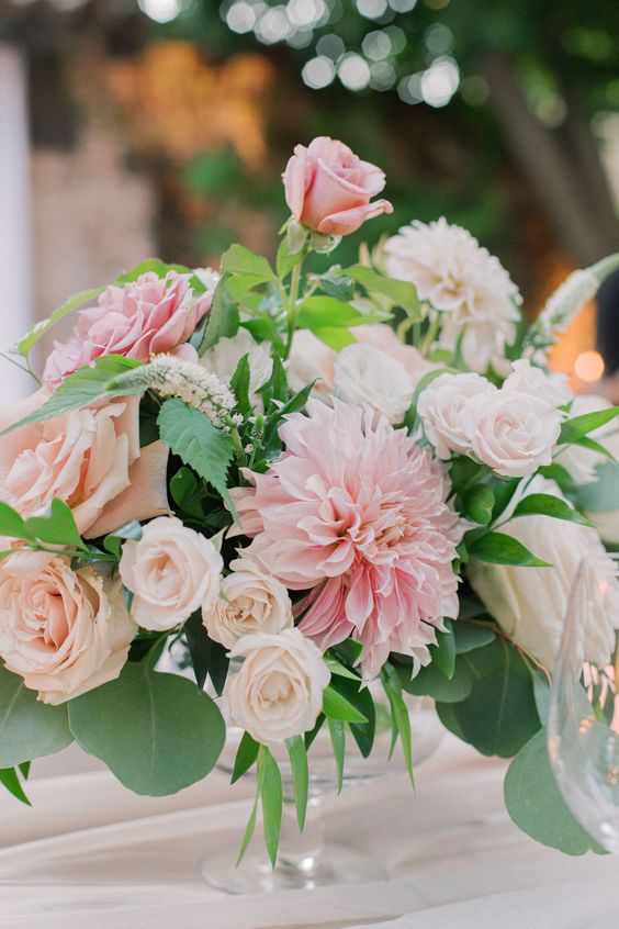 a romantic pink and blush wedding centerpiece of roses and dahlias and greenery for a spring or summer wedding