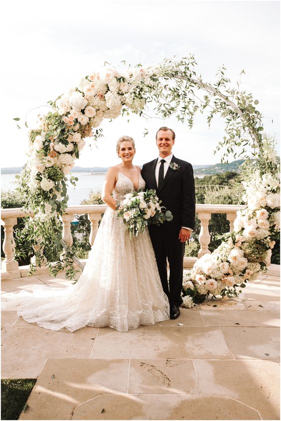 a round wedding arch decorated with greenery, blush and white roses and peonies and some white hydrangeas is a chic idea