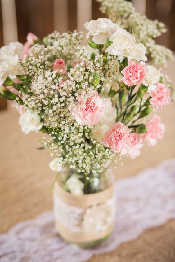 a rustic wedding centerpiece of baby's breath and pink and white carnations is a lovely idea for a rustic wedding