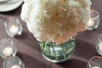 a simple and classic white carnation wedding centerpiece surrounded with candles is a lovely idea for a modern wedding