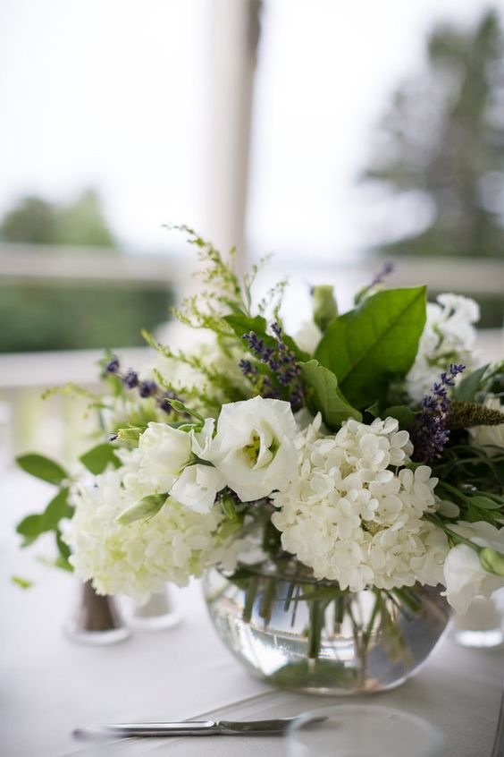 a simple and lovely wedding centerpiece of white roses and hydrangeas, lavender and leaves is a cool idea for spring or summer