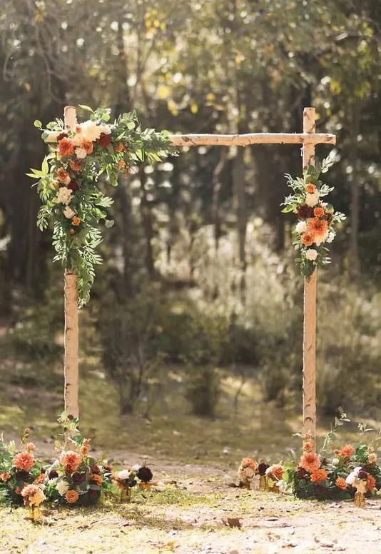 a simple and stylish rustic wedding arch of branches, greenery, white, rust and burgundy blooms and deep purple touches