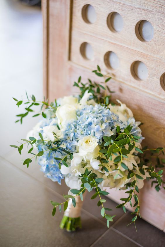 a simple and stylish wedding bouquet of white roses, blue hydrangeas and greenery plus a neutral wrap is wow