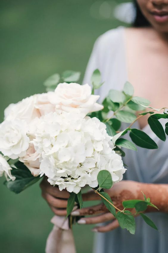 a simple wedding bouquet of white hydrangeas and blush roses plus some greenery for a spring or summer bride