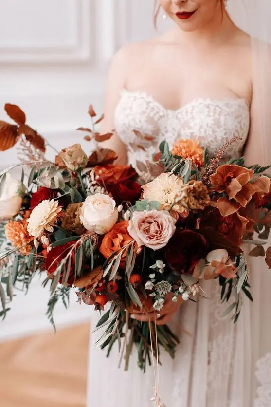 a sophisticated fall wedding bouquet with burnt orange, orange, blush and neutral blooms, berries and textural greenery, dark foliage