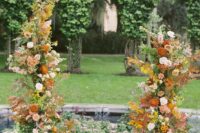 a spectacular fall wedding altar decorated with greenery, blush and rust dahlias, some branches and twigs is wow