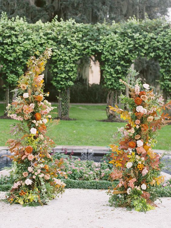 a spectacular fall wedding altar decorated with greenery, blush and rust dahlias, some branches and twigs is wow