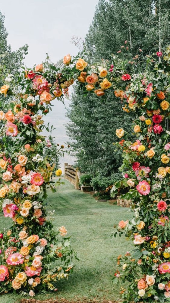 a stunning wedding arch covered with greenery, white, blush and yellow roses and coral peonies is a gorgeous idea