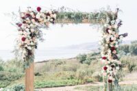 a stylish and contrasting boho wedding arch decorated with greenery, white, blush and burgundy dahlias is a lovely idea for the fall
