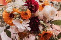 a stylish fall wedding bouquet of white roses and daisies, burgundy and orange dahlias and gerberas, some greenery