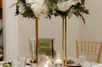 a stylish tall wedding centerpiece of white roses and hydrangeas, greenery and floating candles is a lovely idea for a spring or summer wedding