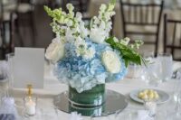 a stylish wedding centerpiece of blue hydrangeas and white roses and greenery is a classyc idea for a rustic or coastal wedding