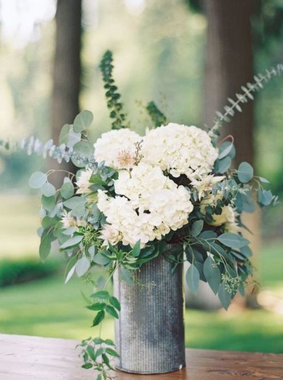 a stylish wedding centerpiece of white hydrangeas and other blooms, greenery of various kinds is a cool idea