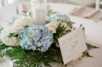 a stylish wreath wedding wreath with blue and white hydrangeas, greenery and a candle in the center is a catchy idea