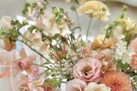 a subtle dimensional wedding centerpiece of peachy dahlias, blush and pink blooms, greenery and some neutral fillers