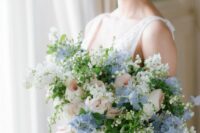 a subtle wedding bouquet of blue hydrangeas, blush roses, some white fillers and greenery for a spring or summer bride