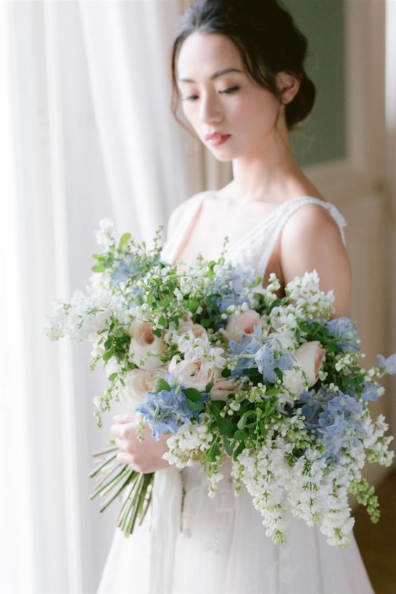 a subtle wedding bouquet of blue hydrangeas, blush roses, some white fillers and greenery for a spring or summer bride