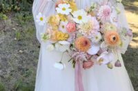 a subtle wedding bouquet of pink and yellow dahlias, ranunculus, poppies and long pink ribbons for a spring or summer wedding
