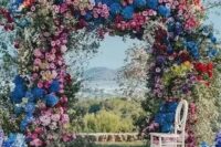 a super lush and bold floral wedding arch with blooming branches and flowers of all shades possible and with greenery