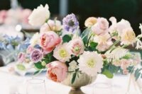 a super lush and chic pastel wedding centerpiece of pink roses and peony roses, lilac peony roses and purple ranunculus, greenery and dahlias