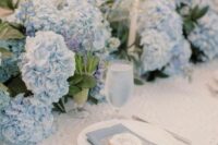 a super lush blue hydrangea wedding table runner plus candles and some bulbs is a gorgeous idea for spring and summer