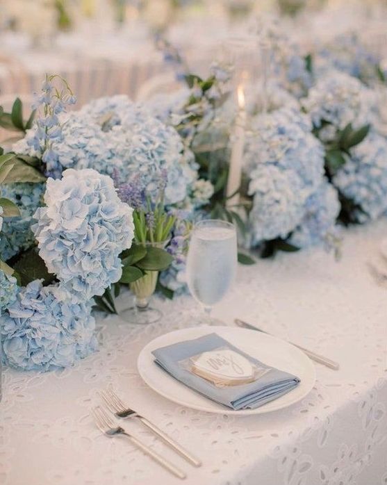 a super lush blue hydrangea wedding table runner plus candles and some bulbs is a gorgeous idea for spring and summer