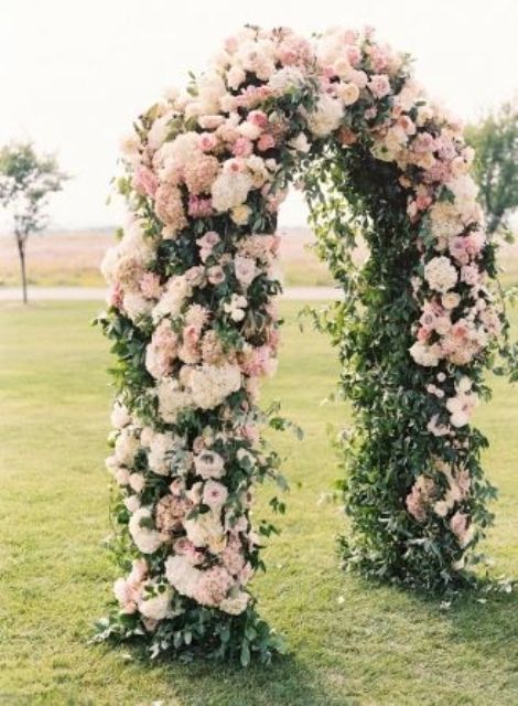 a super lush pink and blush wedding arch with hydrangeas and roses and lots of greenery for a garden wedding