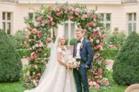 a super lush wedding arch done with greenery, with blush and hot pink roses and dahlias looks very beautiful and perfectly matches the location