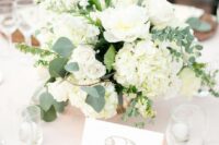 a textural white wedding centerpiece of roses, hydrangeas, greenery and some fillers is a very cool and lovely idea