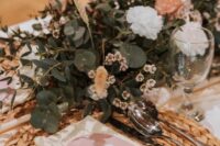a textured and dimensional wedding centerpiece of eucalyptus, waxflowers, grasses, white and coral carnations