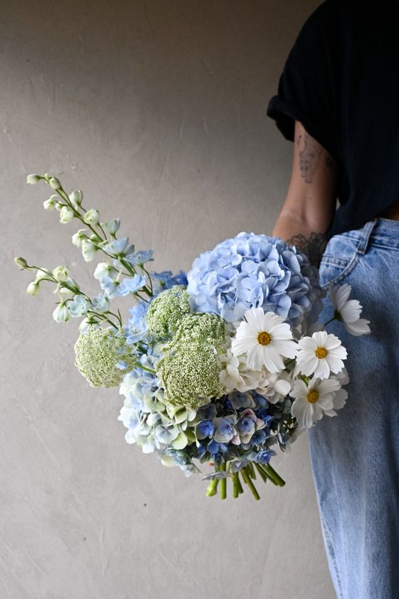 a unique wedding bouquet of blue hydrangeas, white blooms, fillers is a catchy idea for a blue wedding