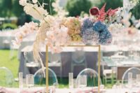 a unique wedding centerpiece of blue and greeneyr hydrangeas, blush orchids, ranunculus and lunaria for a whimsical wedding