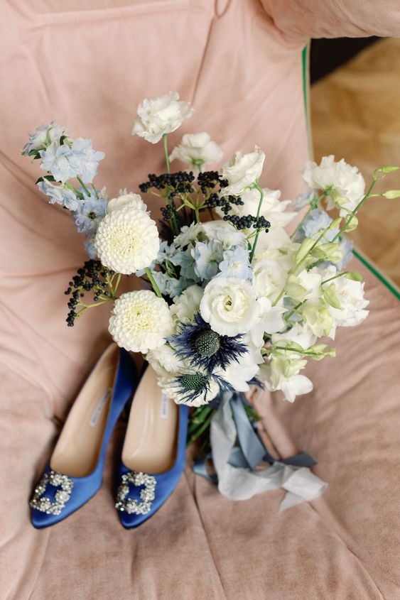 a very subtle wedding bouquet of white and pale blue blooms, dark berries and some thistles catches an eye with texture