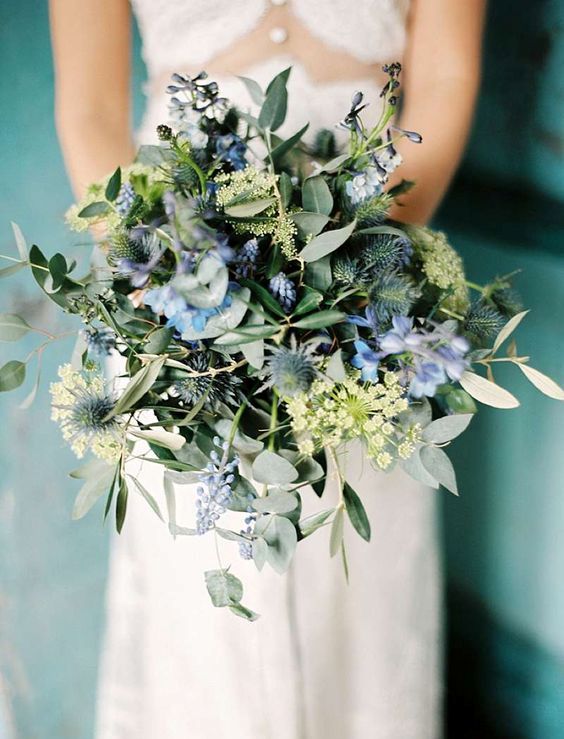 a very textural wedding bouquet with blue blooms, thistles, greenery, berries and some fillers is a very cool idea