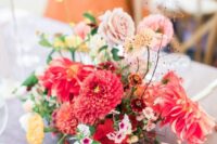 a vibrant wedding arrangement of blush and red dahlias, pink roses and yellow carnations and some twigs for a summer wedding