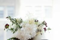 a white wedding bouquet spruced up with greenery and touches of burgundy blooms plus a striped bow