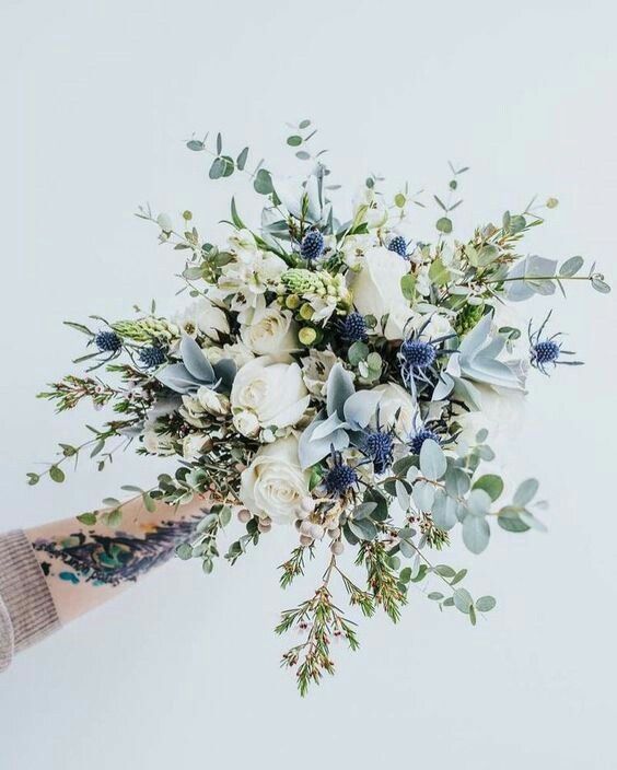 an airy wedding bouquet of white roses, berries, thistles, greenery is a lovely idea for a spring or summer wedding