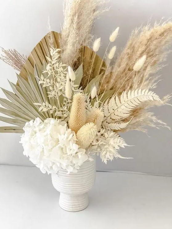 an airy wedding centerpiece of white hydrangeas, bunny tails, dried fronds and leaves is a textural and very creative idea