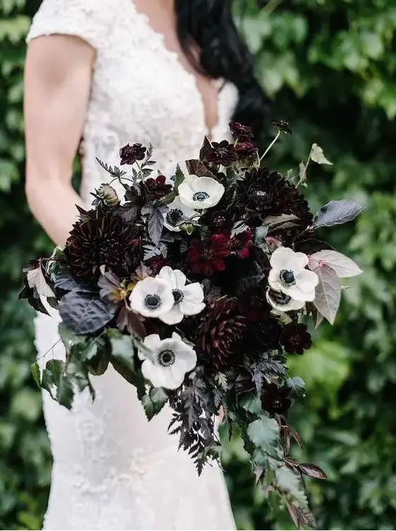 an elegant wedding bouquet with white anemones, dark purple dahlias and cascading greenery