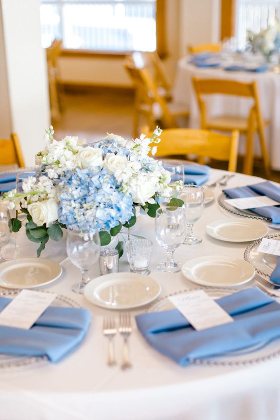 an elegant wedding centerpiece of blue and white hydrangeas and white roses is a stylish idea for spring and summer