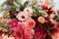an extra bold wedding centerpiece of pink dahlias, orange dahlias, burgundy and purple blooms, dark foliage and greenery