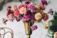 an eye-catching wedding centerpiece of a gold vase with blush, pink and purple carnations is a lovely idea for a bold wedding