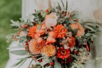an orange wedding bouquet of dahlias, peony roses, gerberas, greenery and berries is a cool idea for a fall bride