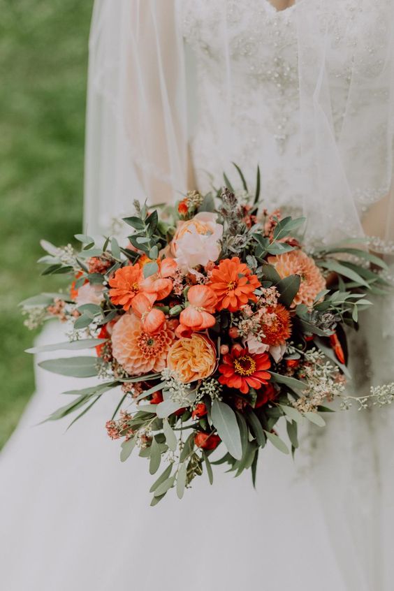 an orange wedding bouquet of dahlias, peony roses, gerberas, greenery and berries is a cool idea for a fall bride