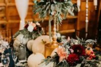beautiful and lush fall rustic wedding decor with pumpkins, greenery, pink and red blooms including dahlias and candles in gold candleholders