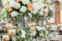 bold and tall wedding centerpiece of white tulips, hydrangeas and orange carnations and greenery plus matching arrangements on the table