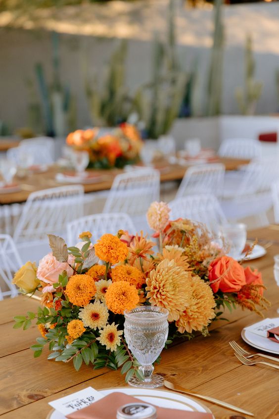 a beautiful and bold wedding centerpiece of marigolds, dahlias, roses, greenery and leaves is a cool solution for a fall wedding