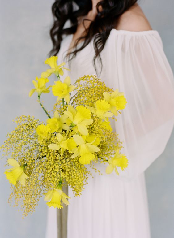 a bold spring wedding bouquet with mimosa and daffodils is a bright touch of color perfect for a neutral bridal look