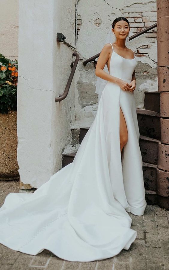 a beautiful modern wedding ballgown with spaghetti straps, cutout sides and a thigh high slit plus a train is a gorgeous idea for  amodern bride