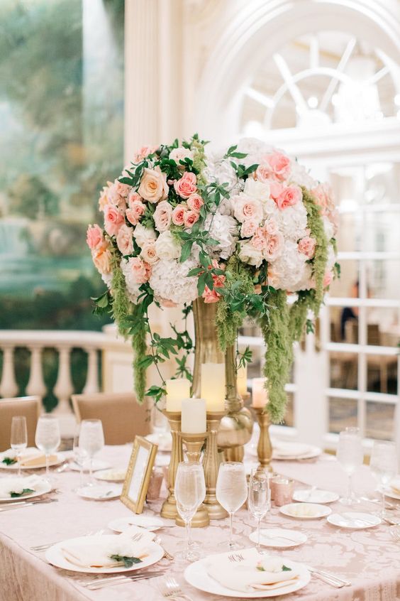 a delicate pastel wedding centerpiece of white hydrangeas, blush roses, greenery and cascading green amaranthus
